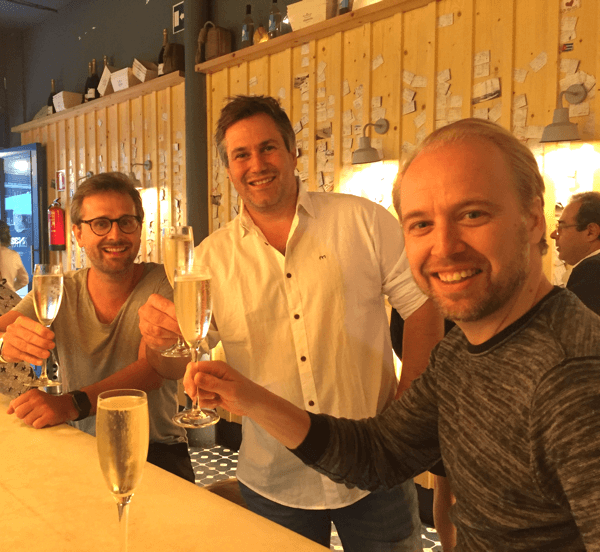 Our colleagues Jonas, Alexander and Alex are drinking sparkling wine in a bar.