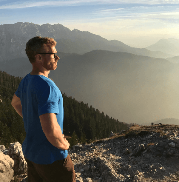 Unser Kollege Arno steht beim Imago Wandertag mit stolz geschwellter Brust auf dem Berg, den er gerade bestiegen hat und schaut in die Ferne.