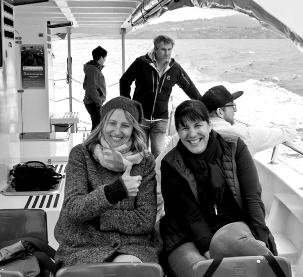 Our colleagues on a boat tour: Veronika and Miriam are sitting and laughing at the camera, Micky sits behind them with his backs to the camera and Alexander looks meaningfully into the distance.